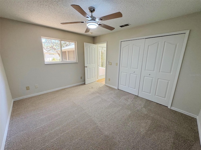 unfurnished bedroom featuring visible vents, baseboards, carpet, a closet, and a textured ceiling