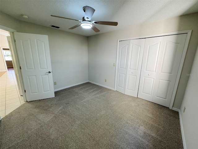 unfurnished bedroom featuring tile patterned flooring, visible vents, carpet floors, a closet, and a textured ceiling