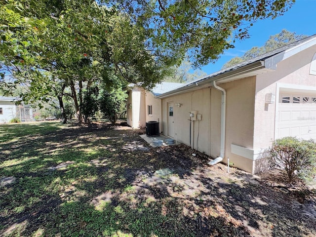 view of property exterior with central AC unit, a garage, and stucco siding