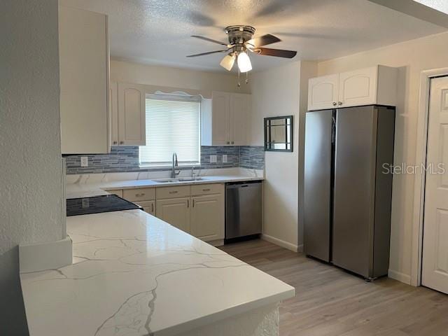 kitchen featuring backsplash, light wood-style floors, appliances with stainless steel finishes, and a sink