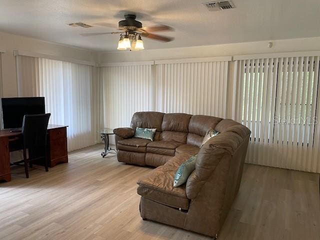 living area featuring visible vents, light wood-type flooring, and ceiling fan