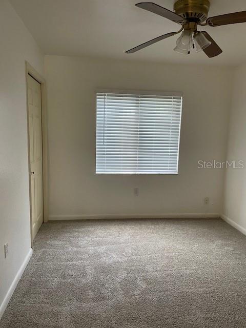 empty room with baseboards, carpet floors, and ceiling fan