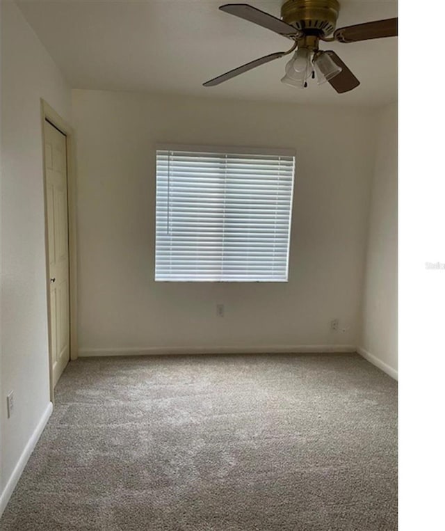 unfurnished room with a ceiling fan, carpet, and baseboards