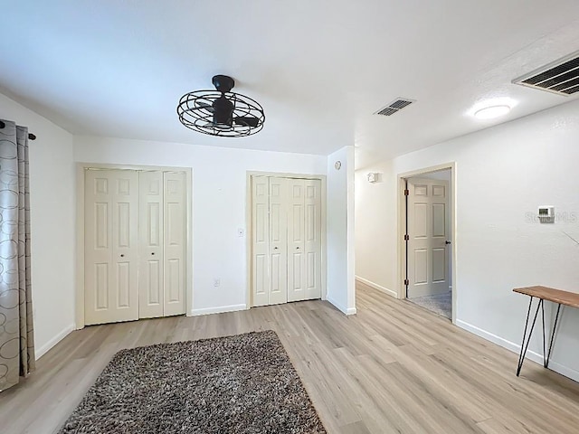 interior space with baseboards, visible vents, light wood-type flooring, and a ceiling fan