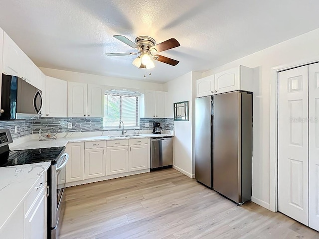kitchen featuring ceiling fan, a sink, light wood-type flooring, and appliances with stainless steel finishes