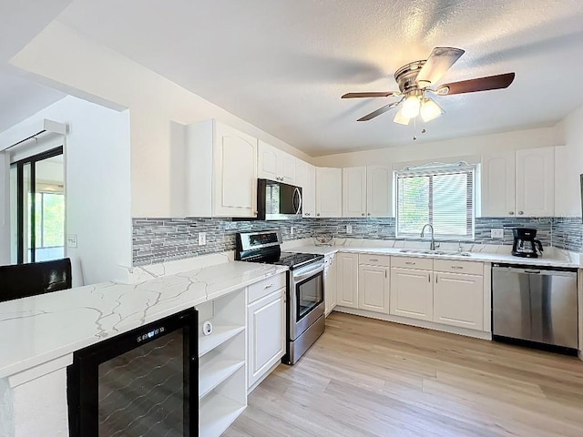 kitchen featuring a sink, tasteful backsplash, wine cooler, and appliances with stainless steel finishes