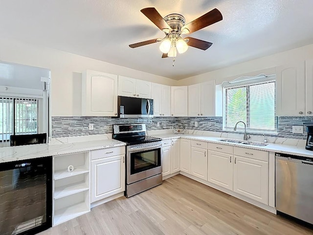 kitchen featuring a sink, light wood finished floors, tasteful backsplash, beverage cooler, and stainless steel appliances