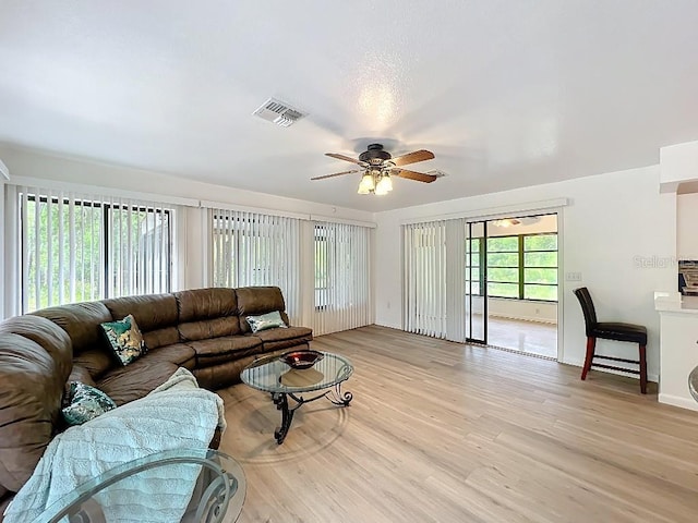 living room featuring light wood-style flooring, visible vents, and ceiling fan