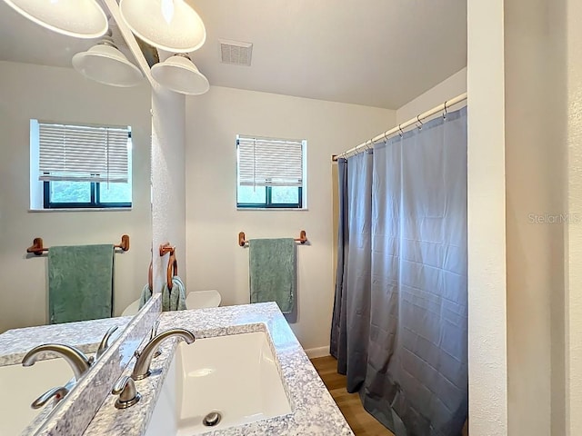 full bathroom with visible vents, wood finished floors, vanity, and a healthy amount of sunlight
