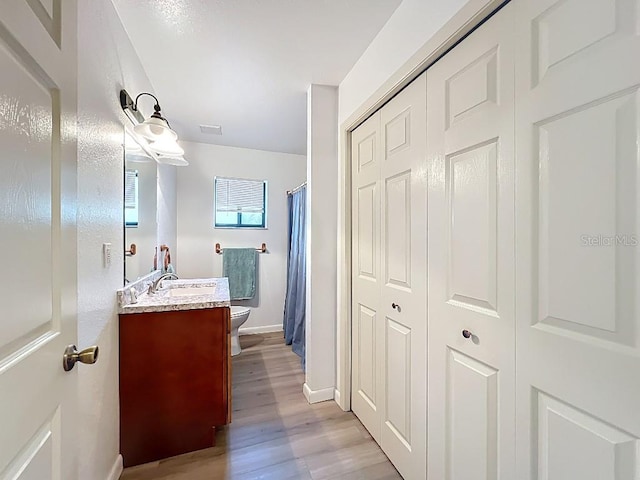 full bathroom featuring vanity, toilet, baseboards, curtained shower, and wood finished floors