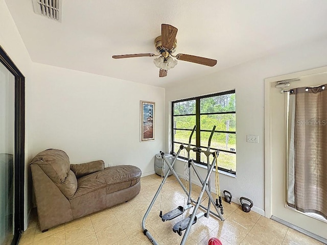 workout room featuring light tile patterned floors, visible vents, baseboards, and ceiling fan