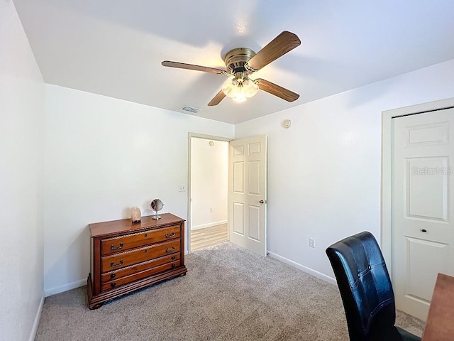 carpeted home office featuring visible vents, baseboards, and ceiling fan