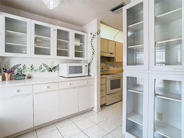 kitchen featuring visible vents, under cabinet range hood, light countertops, light tile patterned floors, and white appliances