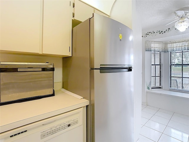 kitchen with dishwasher, light countertops, light tile patterned floors, freestanding refrigerator, and a ceiling fan