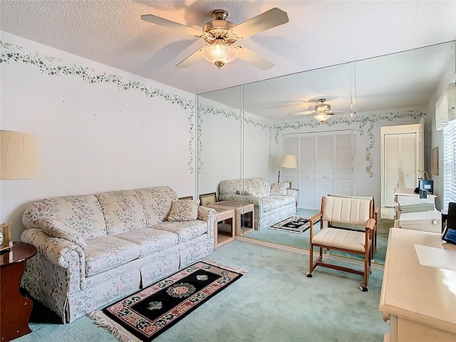 living area featuring carpet, ceiling fan, and a textured ceiling