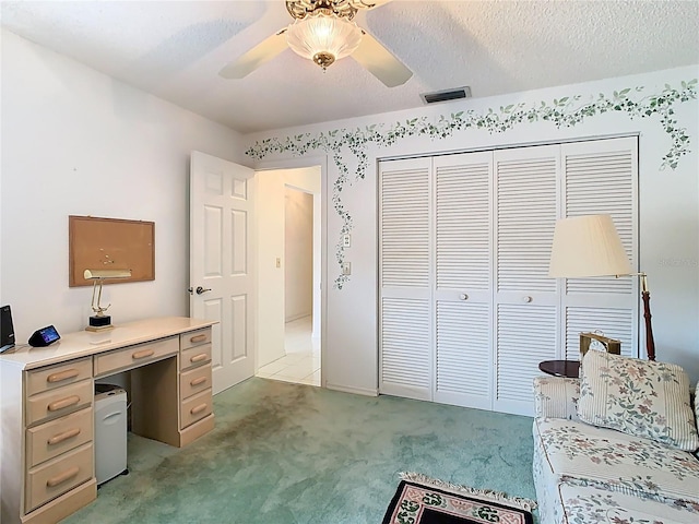 office featuring a textured ceiling, ceiling fan, visible vents, and light carpet