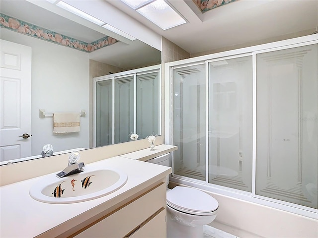 full bathroom with bath / shower combo with glass door, toilet, and vanity