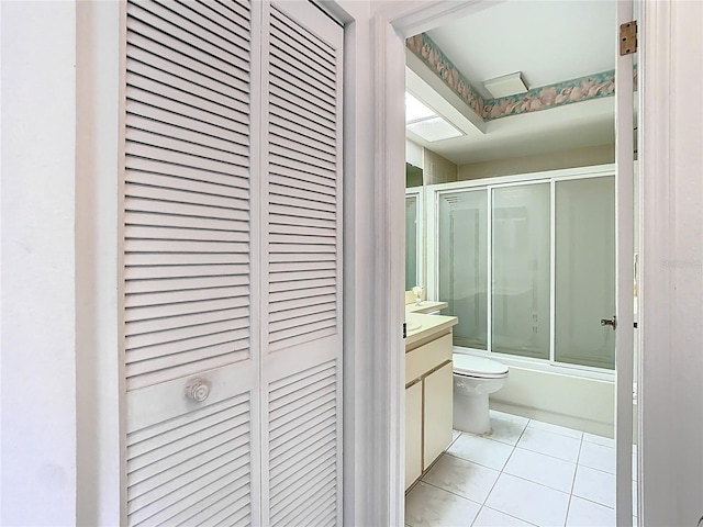 bathroom with bath / shower combo with glass door, toilet, a closet, tile patterned floors, and vanity