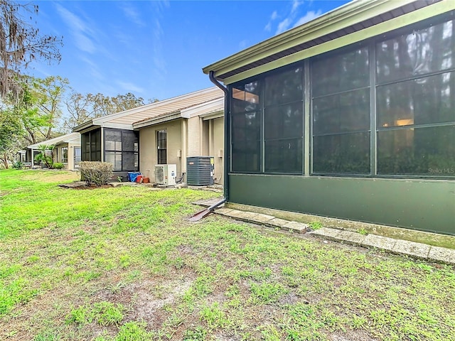 view of side of home featuring ac unit, central air condition unit, a yard, and a sunroom