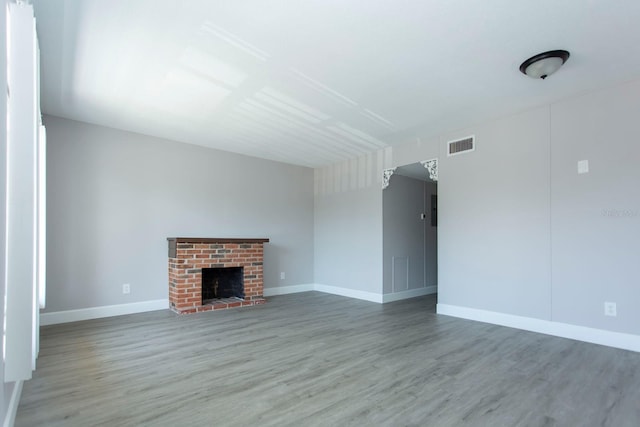 unfurnished living room featuring visible vents, a fireplace, baseboards, and wood finished floors