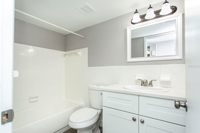 bathroom featuring visible vents, toilet, vanity, bathing tub / shower combination, and tile walls