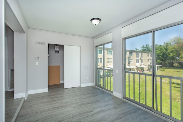 empty room with wood finished floors, visible vents, and baseboards