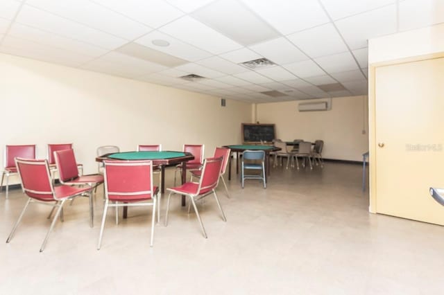 dining space featuring an AC wall unit, visible vents, and a drop ceiling