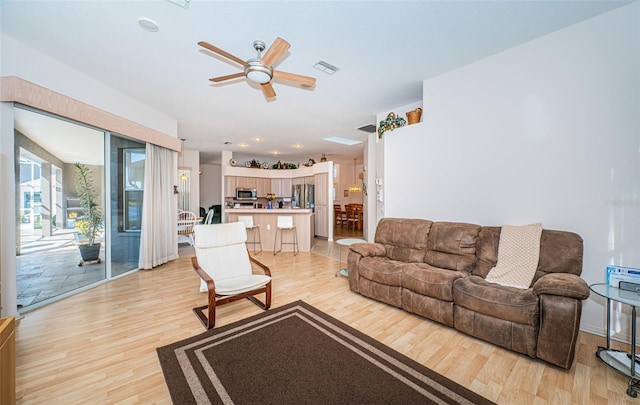 living area featuring a ceiling fan, visible vents, and light wood-type flooring