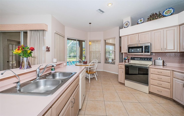 kitchen featuring white appliances, visible vents, light tile patterned flooring, a sink, and light countertops