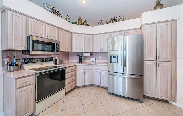 kitchen featuring light countertops, light tile patterned flooring, backsplash, and stainless steel appliances