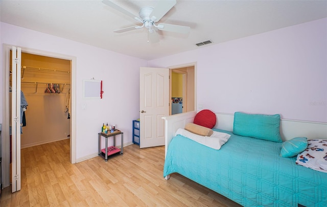 bedroom featuring visible vents, a walk in closet, baseboards, light wood-style flooring, and a closet