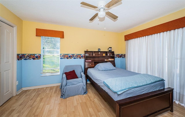 bedroom with light wood-style floors, baseboards, and ceiling fan