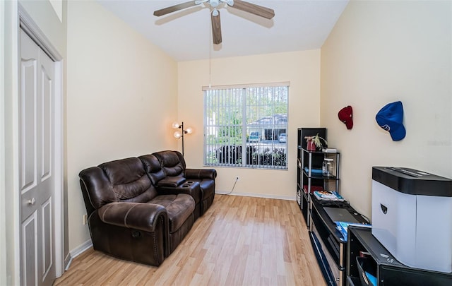 living area featuring baseboards, light wood finished floors, and ceiling fan