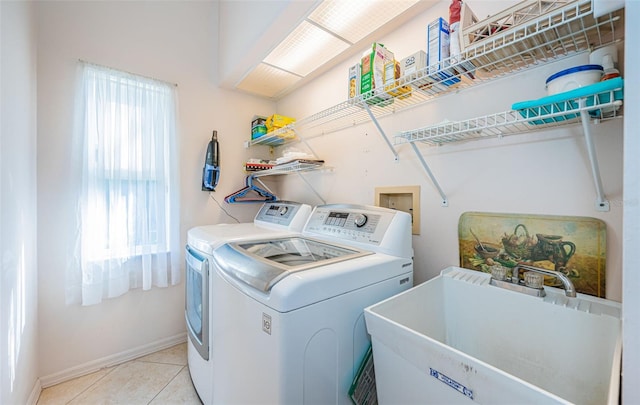 laundry area with washer and clothes dryer, a sink, light tile patterned flooring, baseboards, and laundry area