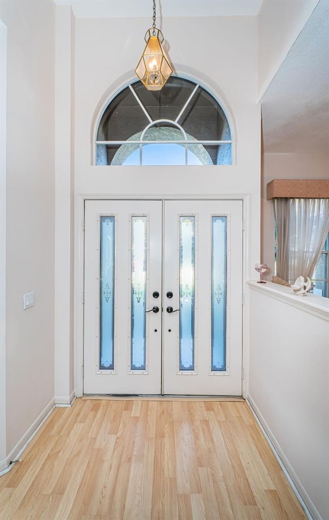 foyer entrance with french doors, baseboards, and wood finished floors