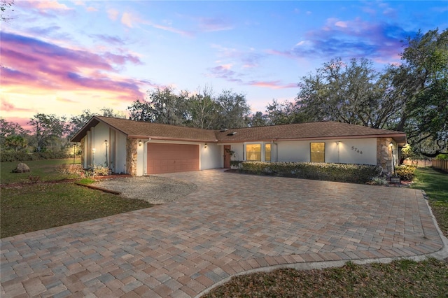 ranch-style home featuring decorative driveway, an attached garage, and stucco siding