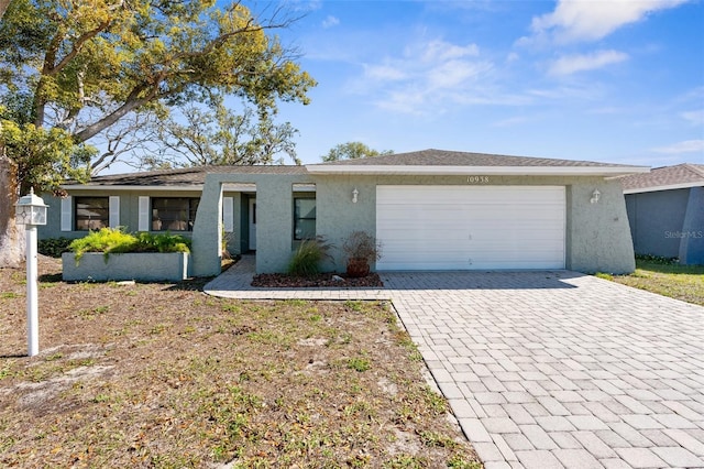 view of front of home featuring decorative driveway, an attached garage, and stucco siding