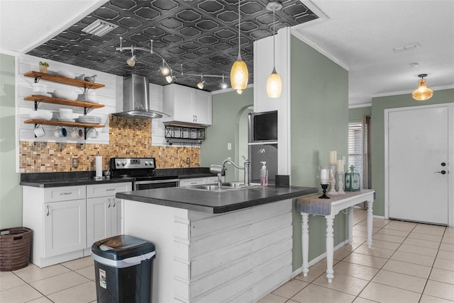 kitchen featuring light tile patterned flooring, a sink, stainless steel range with electric stovetop, dark countertops, and wall chimney exhaust hood