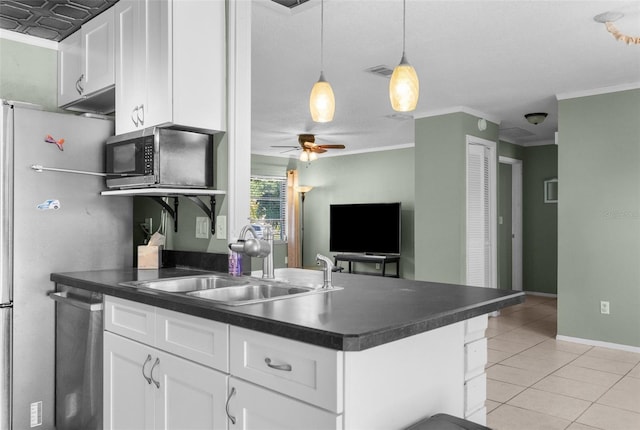 kitchen with dark countertops, light tile patterned floors, appliances with stainless steel finishes, white cabinetry, and a sink