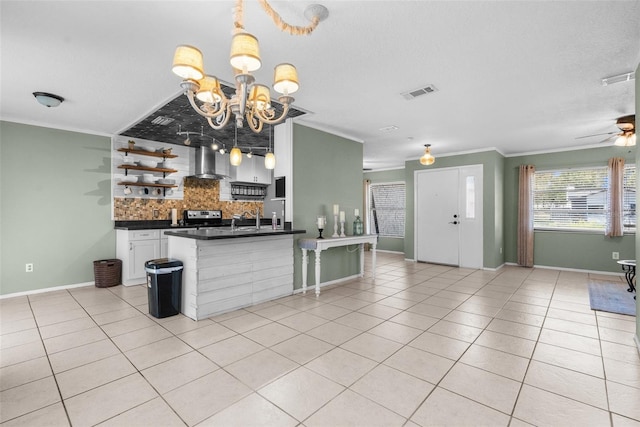 kitchen featuring dark countertops, visible vents, backsplash, wall chimney range hood, and light tile patterned floors