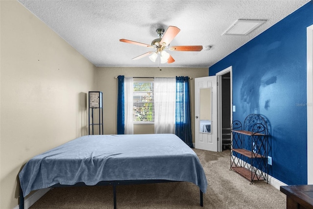 carpeted bedroom with visible vents, baseboards, a textured ceiling, and ceiling fan