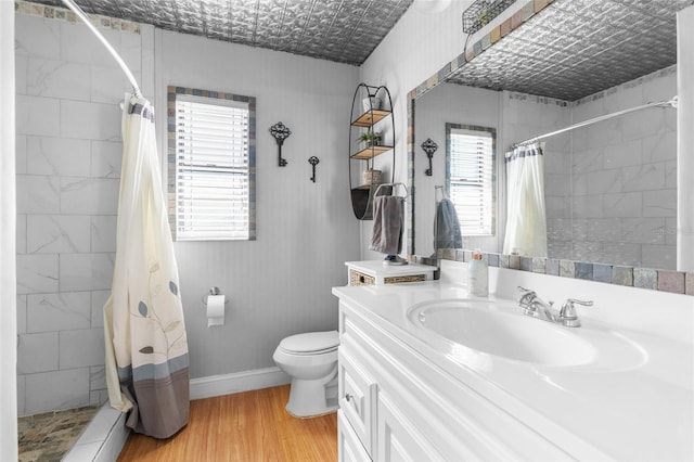 bathroom with toilet, an ornate ceiling, wood finished floors, baseboards, and tiled shower