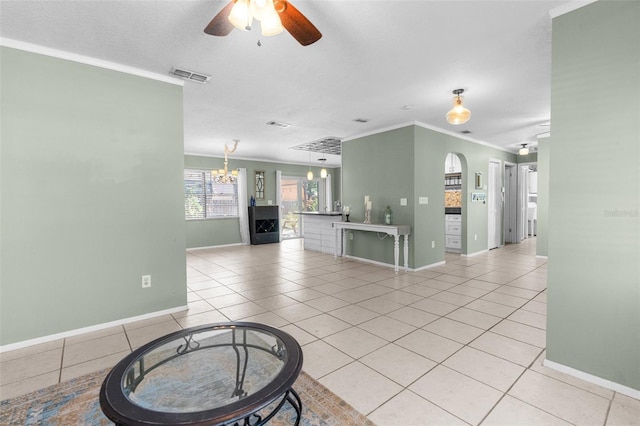 living area featuring light tile patterned floors, baseboards, visible vents, ornamental molding, and ceiling fan with notable chandelier