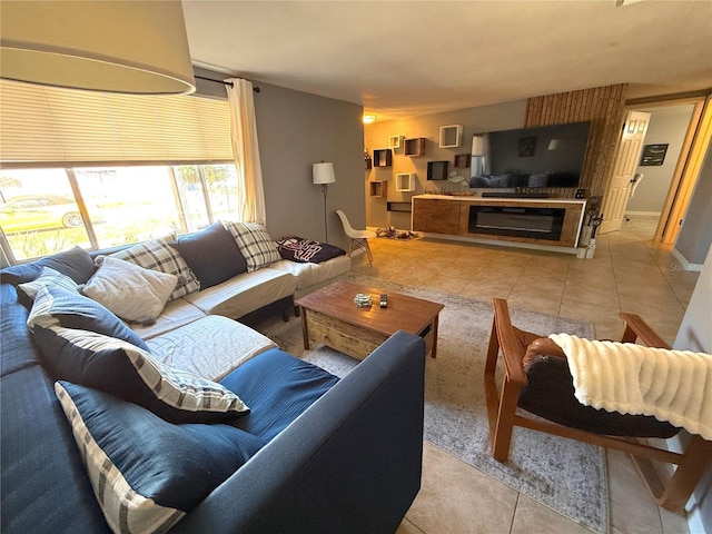 living area featuring a glass covered fireplace, light tile patterned flooring, and baseboards