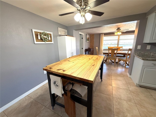 dining space featuring light tile patterned floors, ceiling fan, and baseboards