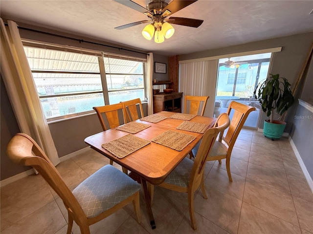 dining area with light tile patterned floors, ceiling fan, and baseboards