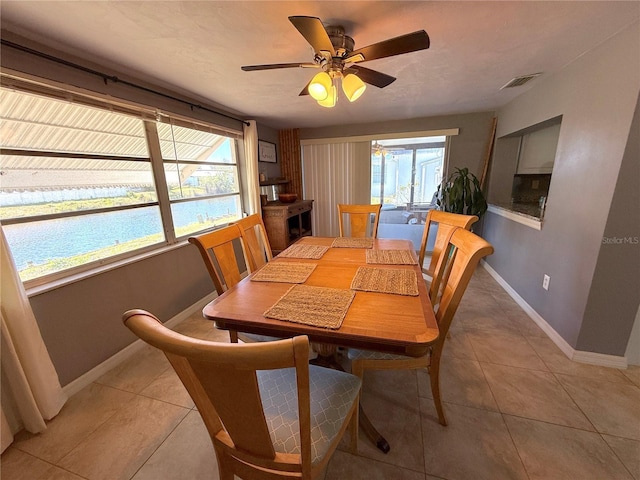 dining space with visible vents, baseboards, a water view, light tile patterned flooring, and a ceiling fan