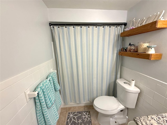 bathroom with a wainscoted wall, toilet, tile walls, and tile patterned flooring