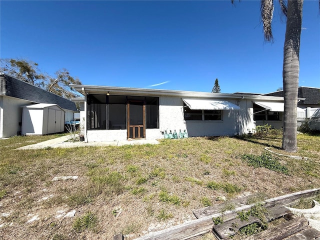 back of property featuring an outbuilding, a storage shed, and a sunroom