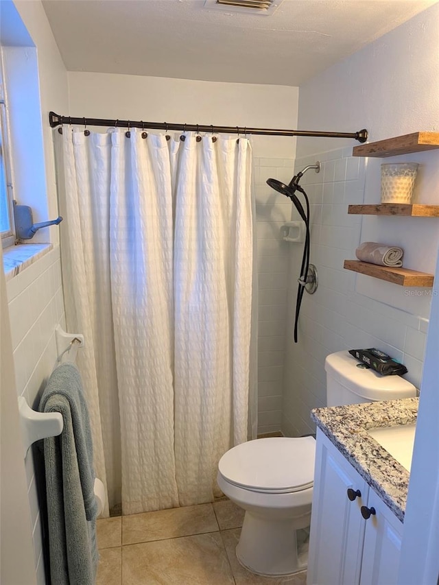 bathroom with vanity, a shower with shower curtain, tile patterned floors, toilet, and tile walls